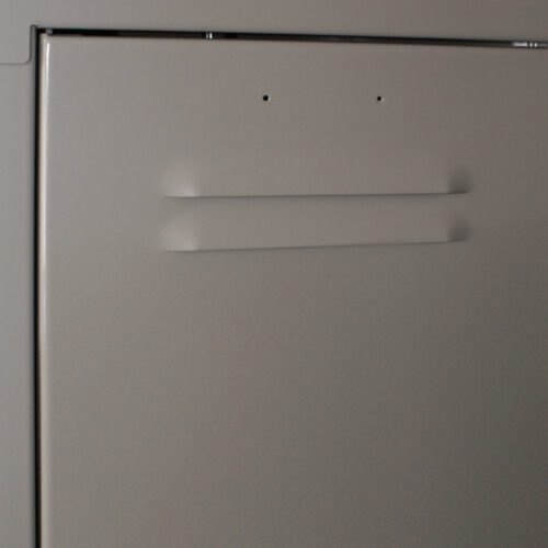 Close-up of a dishwasher door with a minimalist design and two small dots near the top edge, possibly indicating control buttons. The surface is smooth and metallic, reflecting a soft ambient light.