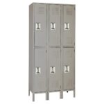 A gray metal locker unit with six compartments arranged in two columns and three rows. Each locker has a vented door with a handle. The unit stands upright with small legs at the bottom.