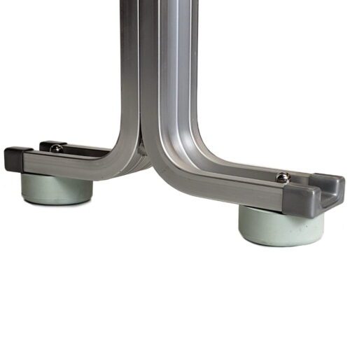 Close-up of a metal frame with curved legs and gray plastic end caps. The legs rest on two small, circular, green rubber pads, likely to protect the floor and prevent slipping. The frame appears to be part of a larger structure.