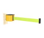 A retractable safety barrier with a bright yellow and black design is mounted on a perforated wall. The belt is extended and is neon green with a black end cap.