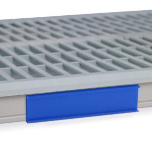 A close-up of a gray slatted ventilated shelf showcases a blue Metro CSM6-BX Color Shelf Marker for MetroMax i Industrial Plastic Shelving, featuring an attached label holder for easy classification against a white background.