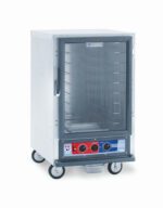 The Metro C515-PXFC-4 C5 1 Series is a half-height stainless steel proofing cabinet on wheels with a transparent door, interior racks, and a bottom control panel featuring two black knobs and several setting buttons. It operates at 220-240V, 50/60Hz, with a power range of 1210-1440W.