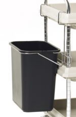 A black Metro BCWB2D Wastebasket is attached to a metal-framed Metro Deep Ledge BC2030 Utility Cart with beige plastic shelves. The cart is equipped with wheels and a handlebar for easy mobility.