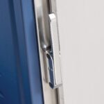 A close-up of the Metro C5-LATCHFLUSH-1 Flush Door Latch Upgrade on a blue and white door, highlighting the sleek silver latch for C5 3 and 1 Series Cabinets.