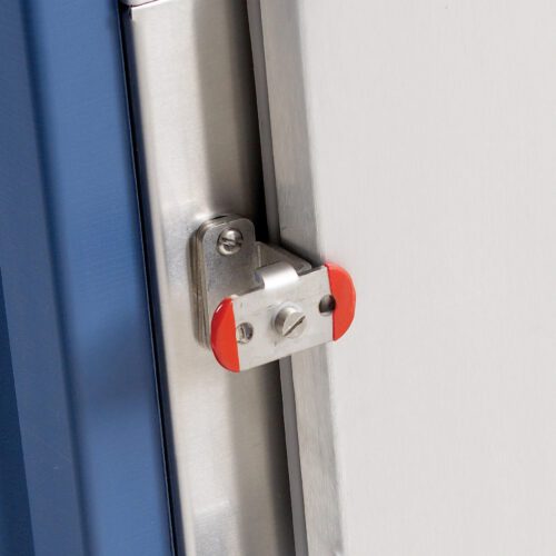 dj3qaplyj74ybzwae0kl83siy15yuoir.jpg Close-up of a Metro C5-TRVL Travel Latch with a red cap on a door, mounted on blue and gray, secured with screws for stability in C5 3 and 1 Series Cabinets.