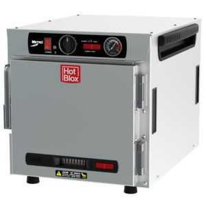 The Metro HBCN4-AS-CT HotBlox is a sleek silver food warmer with a solid door featuring a red logo. It runs on 120V, 60Hz power, has an analog temperature controller, LED indicator, black side handles, four legs for stability, and connects via a NEMA 5-15P plug.