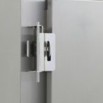 Close-up of a shiny metallic hinge on a 6 Series Cabinet, showcasing its robust design. The hinge securely connects two panels, mounted on a smooth gray fridge surface, similar to the Metro C59-TRVL Travel Latch/Hasp for C5 9, 8, and 6 Series Cabinets.