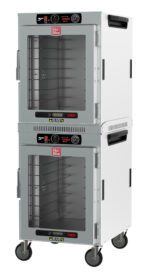 The Metro HBCW16-AC-M HotBlox is a 16-pan insulated dual-cavity stainless steel holding cabinet with clear doors, analog controllers, and NEMA 5-15P. It features control dials, temperature gauges, and wheels for mobility.
