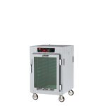 The Metro C585-SFC-LA C5 8 Series Insulated Holding Cabinet, a 1/2-height unit with a full-length clear door and lip load aluminum slides, features a white metal design on wheels, wire shelves, a top digital display, and operates at 120V and 60Hz.