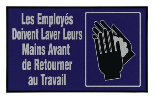 On a Justrite Mat, 194 Fren Employee Wash 3X5, a blue and black sign displays French text: Les Employés Doivent Laver Leurs Mains Avant de Retourner au Travail, with an icon of hands being washed.