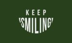 Against a dark green backdrop, KEEP SMILING is in white text, with SMILING arched like a grin, echoing the design of the Justrite Mat in the Keep Smiling 195 3X5 Gn series.
