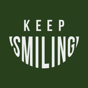Against a dark green backdrop, KEEP SMILING is in white text, with SMILING arched like a grin, echoing the design of the Justrite Mat in the Keep Smiling 195 3X5 Gn series.