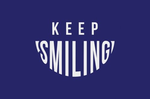 A text graphic on a dark blue background reads KEEP SMILING, with SMILING designed in an elongated, curved style that forms a smile, inspired by the playful aesthetics of the Justrite Mat, 195 Keep Smiling 4X6 Bu collection.