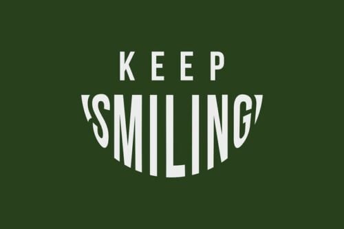 Text on the 4X6 dark green Justrite Mat reads Keep Smiling in white capital letters, with Smiling curved like a smile, capturing an encouraging essence.
