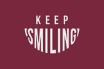Text on a burgundy background reads KEEP SMILING, with SMILING curved upwards like a smile, capturing the cheerful essence of the Justrite Mat, 195 Keep Smiling 4X6 Rd.
