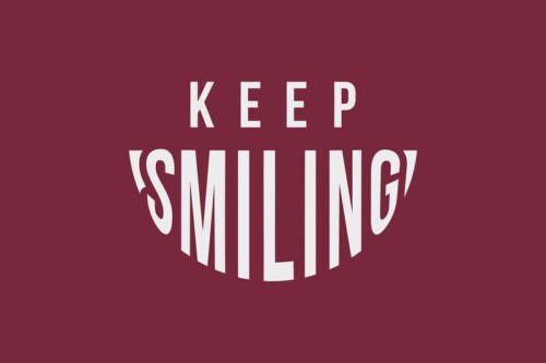 Text on a burgundy background reads KEEP SMILING, with SMILING curved upwards like a smile, capturing the cheerful essence of the Justrite Mat, 195 Keep Smiling 4X6 Rd.