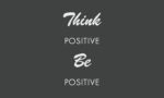 On a dark gray Justrite Mat, the white text Think Positive Be Positive stands out with Think and Be elegantly scripted and Positive in bold sans-serif, creating an inspiring atmosphere on this 3X5 Charmer.