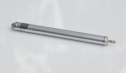 A Justrite Cylinder, F/Cabinets, silver and cylindrical, with a small connector at one end, rests on a plain light surface. It appears to be an electronic or mechanical component, likely functioning as a sensor or actuator.