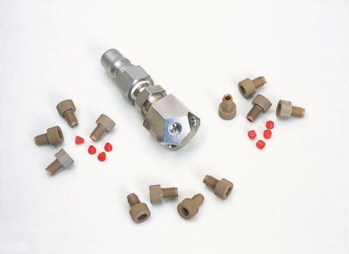 A metal tool with a hexagonal end lies amidst small brown screws and tiny red cylinders on a white surface, reminiscent of parts from a Justrite Manifold W/Ss Fitting F/Hplc.