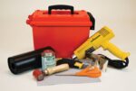 Discover our Justrite Repair Kit, Modified PVC Fabric, offering a variety of crafting tools and materials including a red plastic toolbox, yellow heat gun, black vinyl roll, adhesive can and brush, red roller, utility knife, silver cutter, orange scissors, and gray modified PVC fabric sheet.