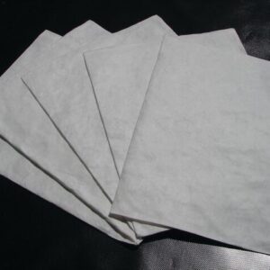 Five sheets of paper, similar to the quality of Justrite Pad Drip Refills 21X23, are fanned out on a dark surface, with lighting accentuating their texture and slight translucency.