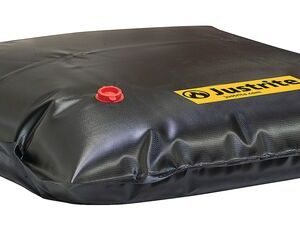The Justrite Drain Cover, Waterfill 30X30, comes with a large black containment pillow featuring a red valve and a yellow Justrite label. Its smooth surface indicates its fully inflated and ready for use.