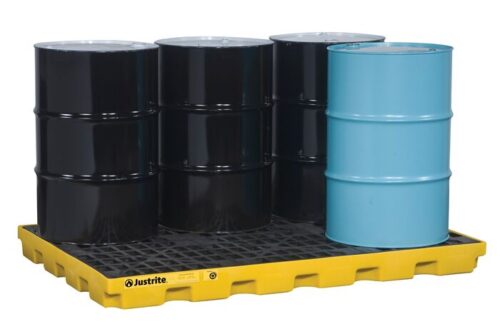 Four metal barrels—three black and one blue—are neatly arranged on a Justrite Accum Ctr, 6 Drum, Ecopoly Yel spill containment pallet against a pristine white background, highlighting the striking contrast.