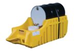 A black and white drum sits on a yellow Justrite Caddy, Drum, Indr/Outdr Eco Yl platform, with two white buckets beneath its faucet. The rectangular platform is designed for efficient spill containment to catch potential leaks.