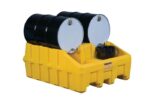 Two black barrels with white tops are stored on a yellow Justrite Drum Mgmt Base, Ecopoly. A smaller black container is placed in front of the barrels.