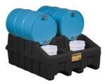 Four blue barrels sit on a Justrite Drum Mgmt Base, Ecopoly, Blk, with two white buckets catching liquid from taps for safe fluid dispensing and storage.