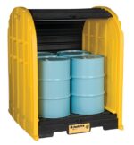 A Justrite Drumshed W/Pllt, 4 Drm, Ecoply with a black interior holds three blue metal drums. Its open front displays the contents and the Justrite logo, offering a perfect blend of functionality and robust design for secure storage needs.