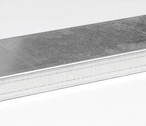 A rectangular metal drain grate with a textured surface and two slots on one side features a rugged design similar to that of a Justrite Shelf, 2G Mini Cabinet. It rests on a light gray background, angled to give depth and dimension.