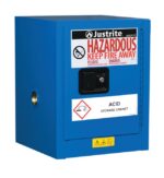 The Justrite Cabinet, Haz Mat Cnttop 4G Sc, is blue with a Hazardous: Keep Fire Away label and marked as an Acid Storage Cabinet. It has a protruding handle and safety icons warning against chemical storage. Perfect for secure storage needs.