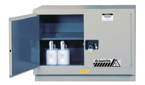 8849042.jpg A gray Justrite Cabinet FMHD CHMC 31G MAN SLV is open, displaying two white chemical containers inside. It features branding, safety labels, and a lockable latch, set against a pristine white background.