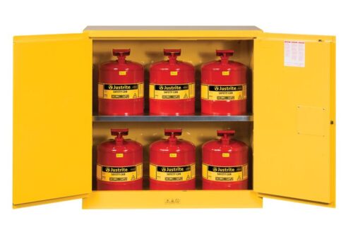A yellow Justrite Cabinet is open, displaying six red Justrite safety cans with handles and spouts. The interior label on the left door shows safety instructions, ideal for securely storing Flam W/Cans 30G Mn Yl items.