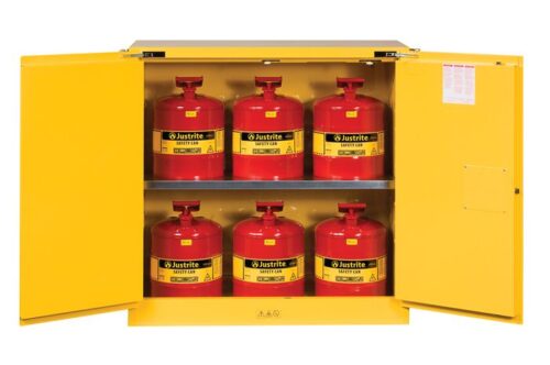 The yellow Justrite Cabinet reveals six red Justrite Safety Can fuel cans—three on each shelf. Safety warning labels are visible inside the cabinets doors.