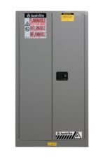 The Flam Sfty 60G Sc Gry Justrite Cabinet, in gray, displays Flammable and Inflammable labels with caution symbols and warnings to keep fire away, designed for the safe storage of hazardous materials.