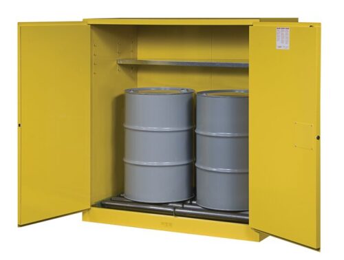 A Justrite Cabinet, Vdrm/Rlr (2)55G Mn Yl, is open to reveal two large grey barrels inside with a metal shelf above for added utility.