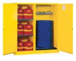 A Justrite Cabinet is open, showcasing red safety containers with yellow labels on the left and a Cmbo Vdrum/Rlr Mn Yel at the bottom right, with safety goggles and gloves on the shelf above.