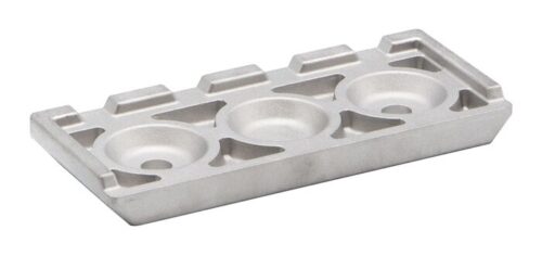 The Justrite Chock, model 3514, has a smooth, shiny silver finish with three central circular indentations surrounded by geometric patterns, suggesting its use in intricate machinery or specialized equipment.