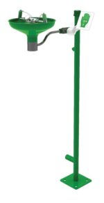 The Justrite H eyewash station features a spout, open stainless steel bowl, and lever. Mounted on a sturdy base with a pole displaying a hand icon, it ensures quick access during chemical emergencies.