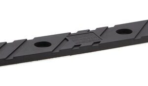A long black rubber strip similar to the Justrite Chock, Mc, Acc, 3012, Rpad is displayed. It has three circular holes with a surface featuring diagonal grooves and a central rectangular Rpad area with a textured pattern.