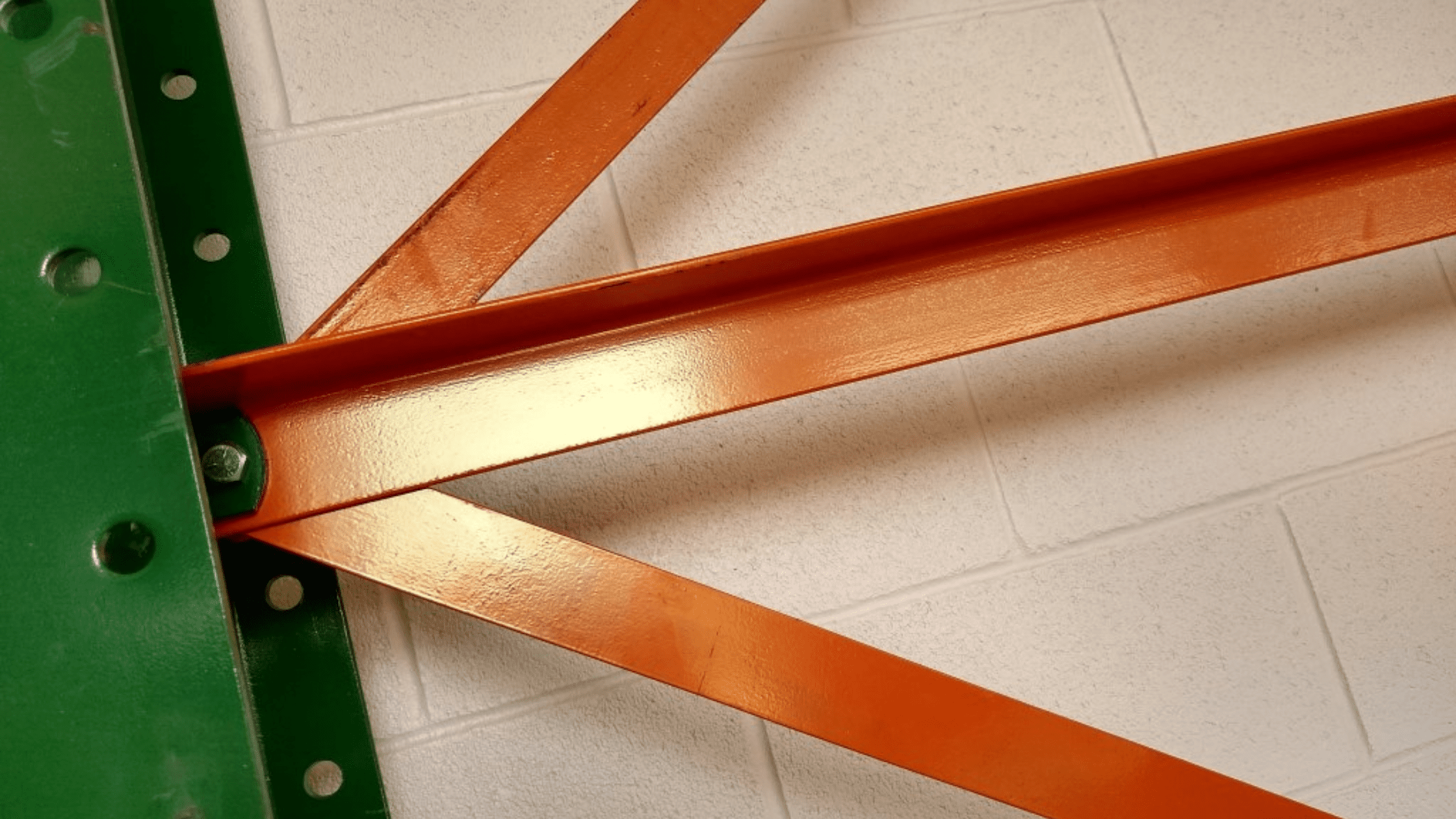 Close-up of an orange cantilever arm and brace bolted to a green upright column