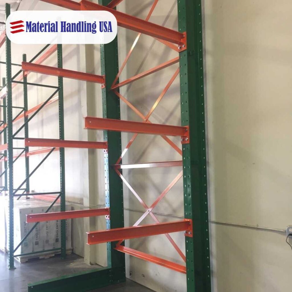 Industrial metal shelving unit with green vertical supports and orange horizontal beams. The unit is placed against a light-colored wall in a warehouse setting. A logo reading Material Handling USA is visible in the top corner.