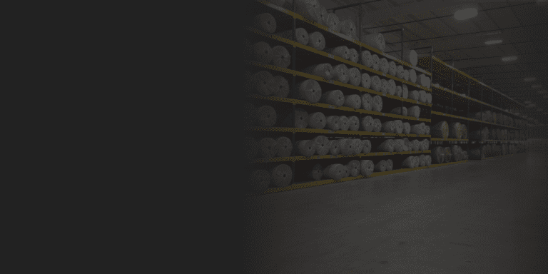 Warehouse aisle of pallet racking loaded with large rolls of carpet
