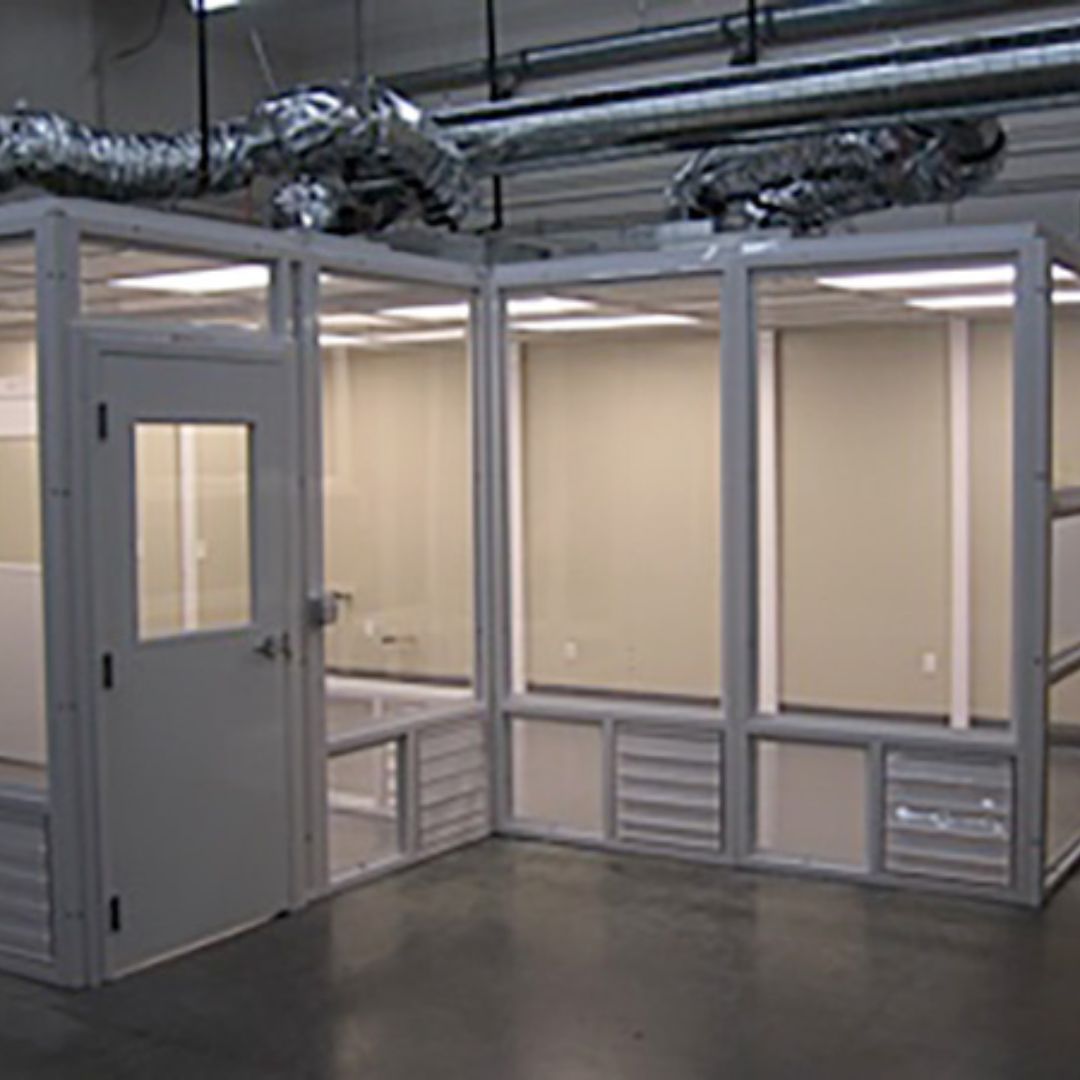 Modular cleanroom with framed vision windows, a personnel door and supply ducts above