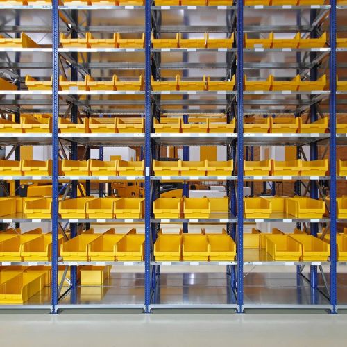 Shelves filled with empty, yellow storage bins in a warehouse setting resemble the meticulous organization of forensic evidence drying cabinets. The bins are neatly organized on blue metal racks, creating a pattern across multiple levels. The floor is clean and reflective, with an otherwise empty background.