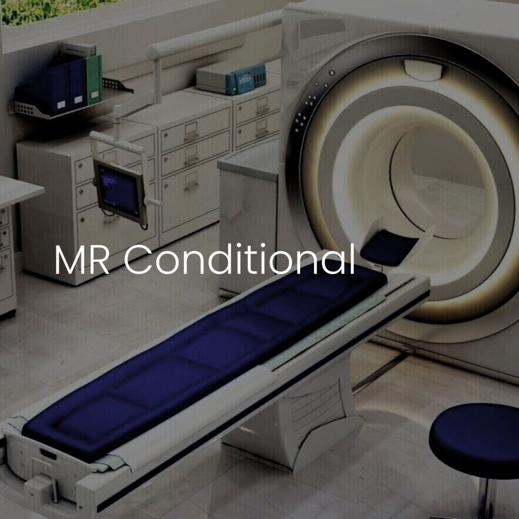 The MRI machine rests in a medical room with a blue padded patient table, framed by Blickman cabinets and shelves. The words MR Conditional softly overlay the image, highlighting the equipments safety features against the sleek backdrop.