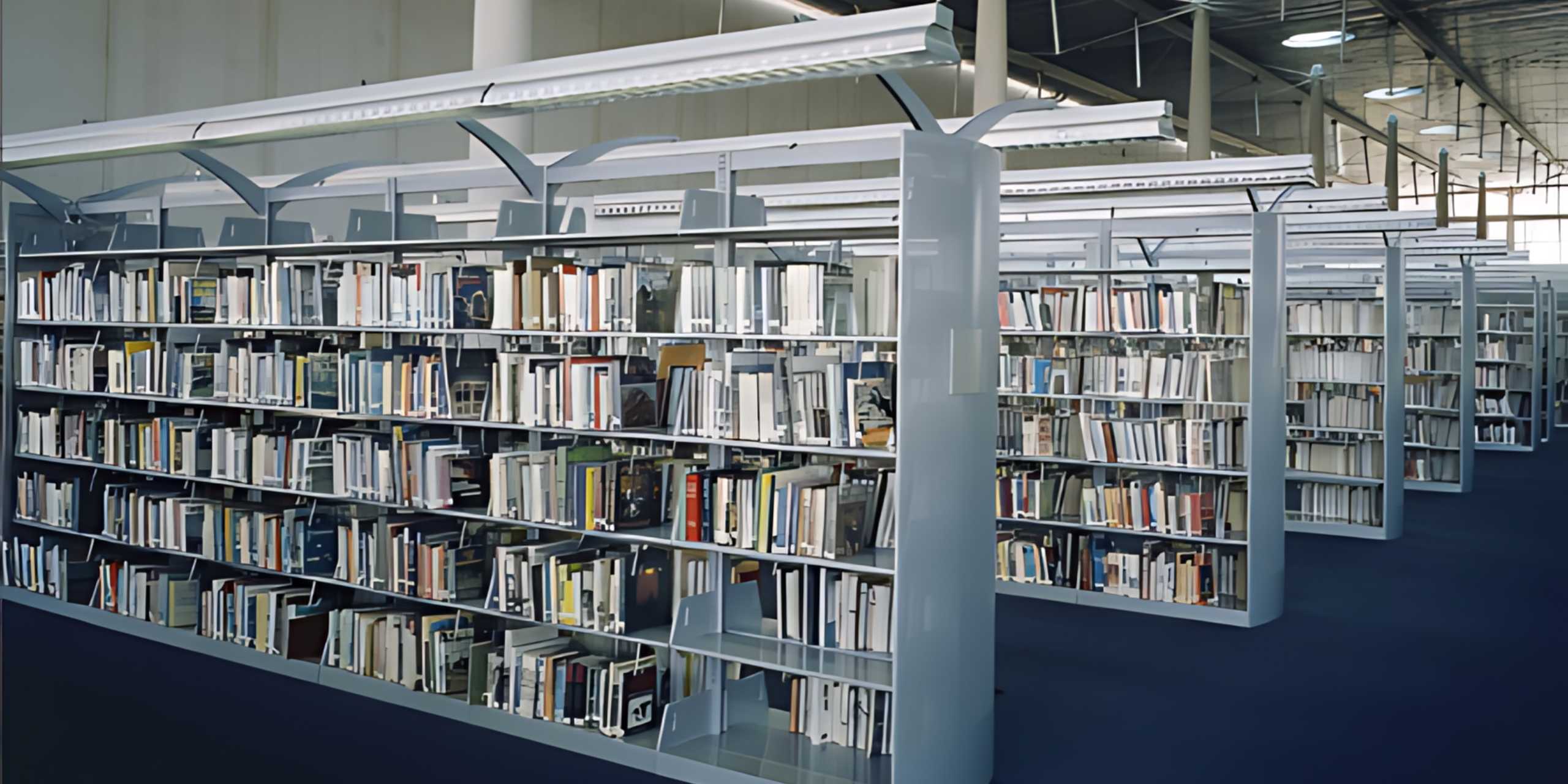 Rows of library book stacks with canopy lighting above the ranges
