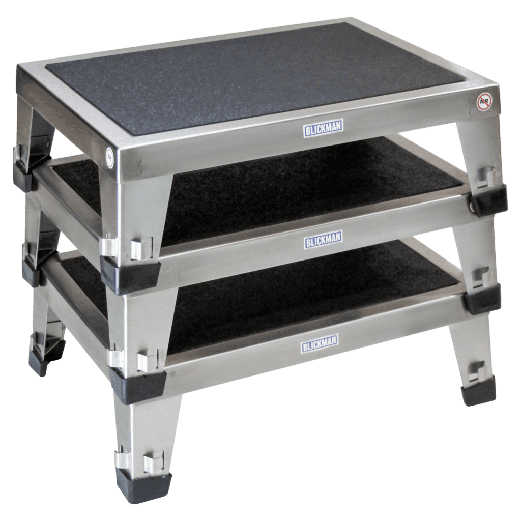 Stacked Blickman metal platforms with rubber surfaces feature sturdy legs and black grips on the corners. These platforms boast labels and a sleek design, making them ideal for industrial or commercial use.